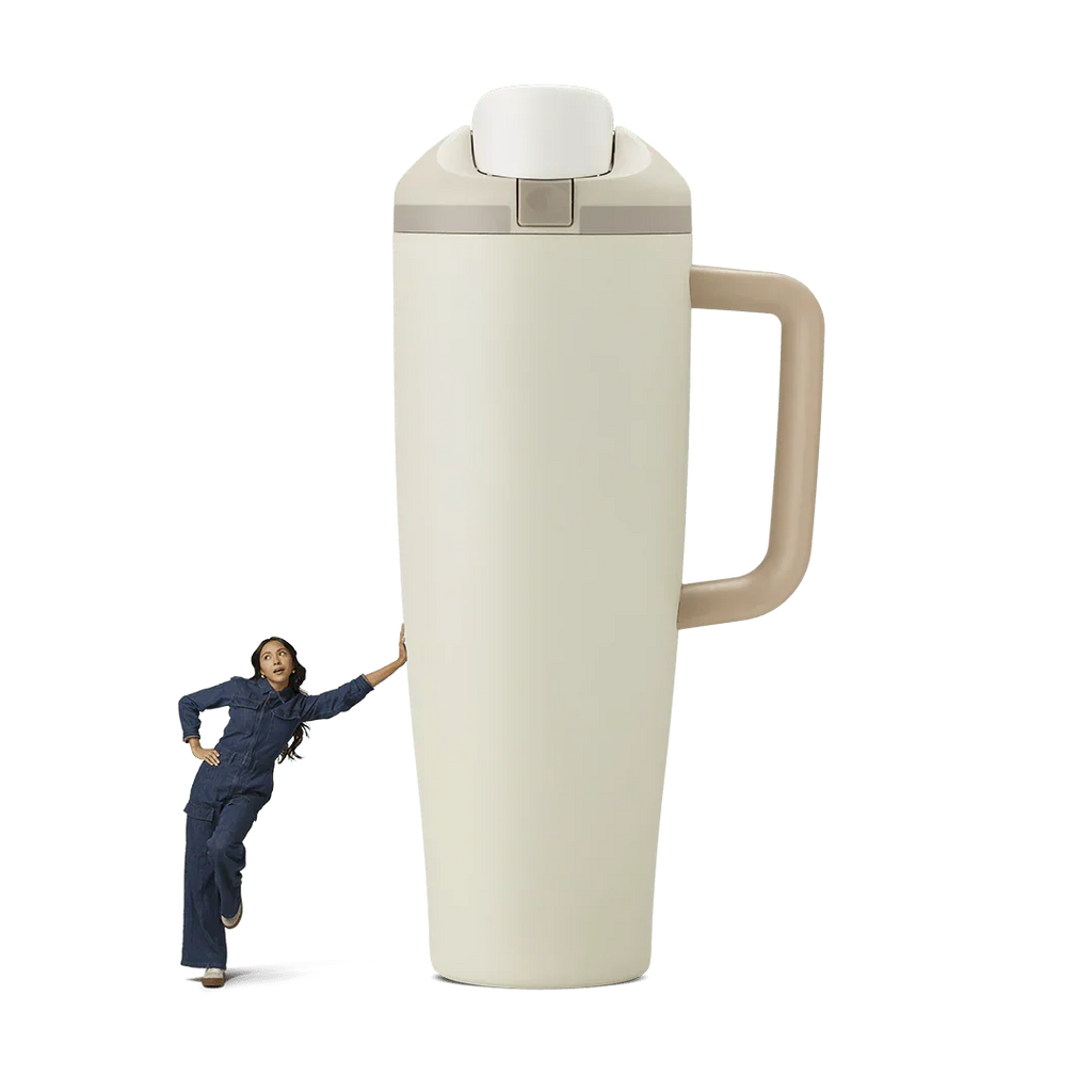 Large beige 40oz lightly toasted Miami tumbler with handle and flip lid, woman in blue jumpsuit leaning on it