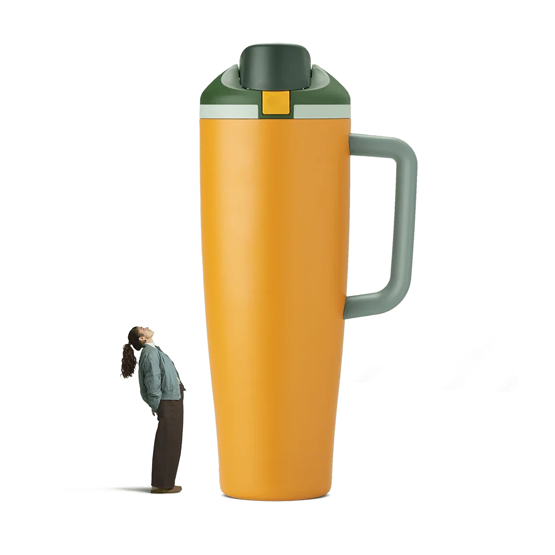 Tall orange and green insulated tumbler with gray handle, standing next to person for size comparison