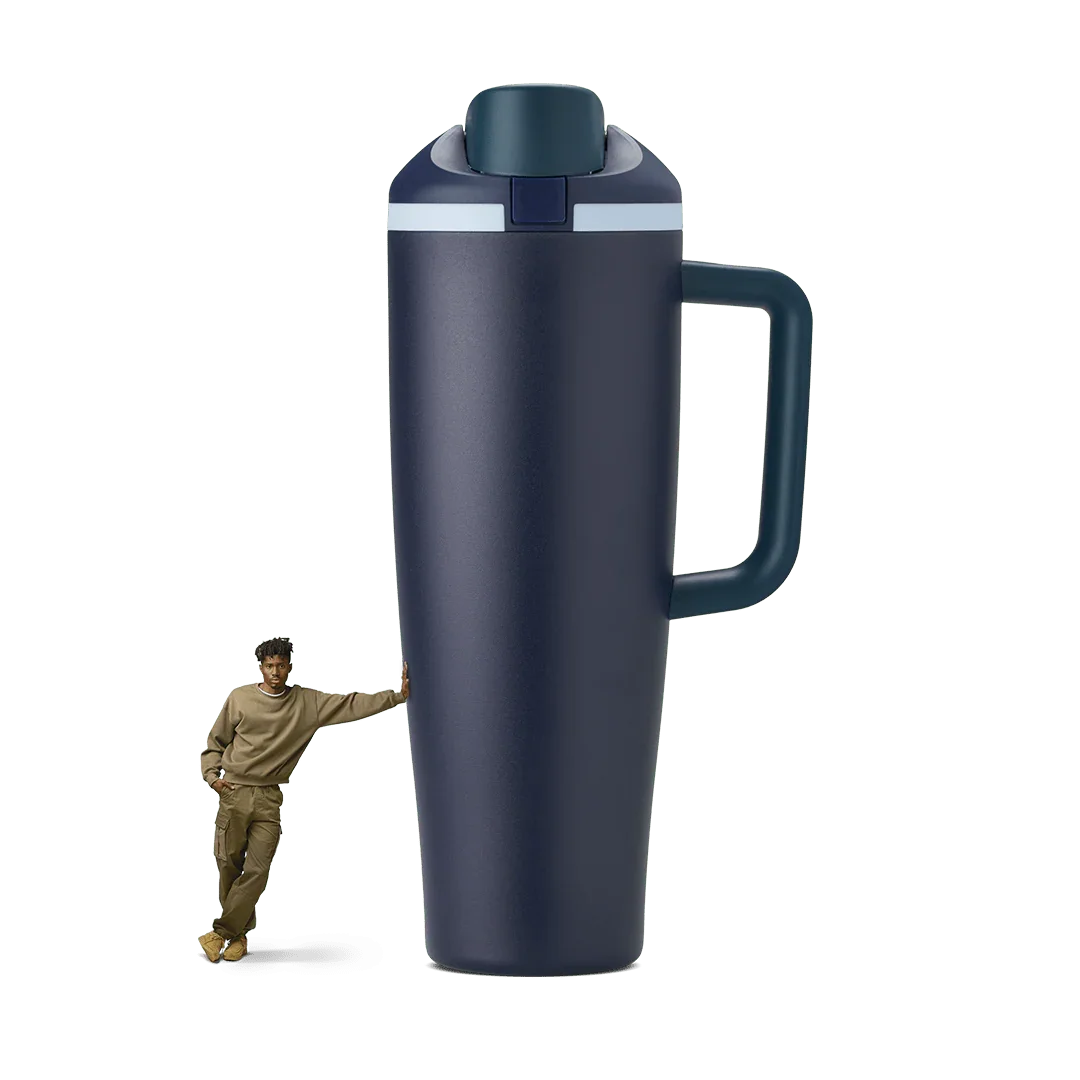 Large navy blue 40oz travel tumbler with handle, shown oversized next to standing person