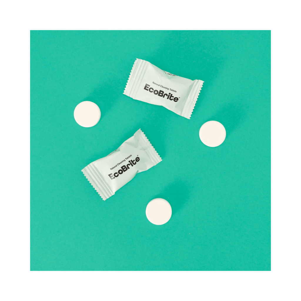 Two EcoBrite natural cleaning tablets in white wrappers and three white round tablets on teal background